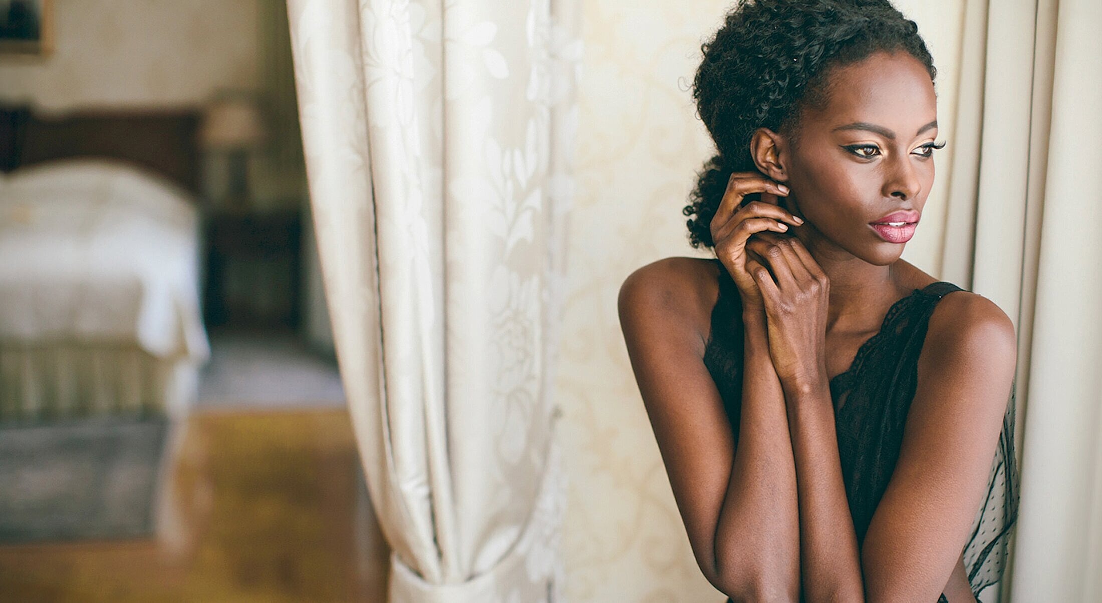 Woman gazing thoughtfully by window.